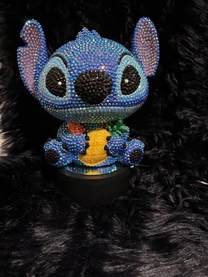 Blue character figure covered by hand in sparkling rhinestones